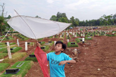 A boy plays with a kite in the Pondok Ranggon Public Cemetery in East Jakarta on Aug. 14. With a limited amount of open space, many children in Jakarta are forced to play in some unusual places, including in this cemetery, which has served as the final resting place of many COVID-19 victims. 