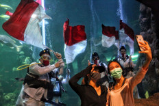 Deep dive: Visitors take a wefie as divers hold a rehearsal of an underwater flag-waving ceremony at Seaworld Indonesia in Ancol, North Jakarta, on Saturday. The annual event was held to commemorate the 75th anniversary of Indonesia's independence. JP/Seto Wardhana
