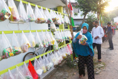 A woman collects a package of staple food containing rice, instant noodles and vegetables at the Villa Pamulang housing complex, South Tangerang, Banten, on Friday. Residents of the housing complex collect funds to buy 150 to 200 packs of food every Friday to be distributed to their neighbors in need. JP/Dhoni Setiawan