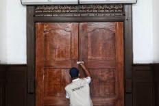 A mosque security guard locks the doors of Cut Meutia Mosque in Central Jakarta on Thursday, September 17, 2020. The city administration has reimposed full large-scale social restrictions to combat a COVID-19 spike in the capital that has strained hospital resources. JP/Seto Wardhana