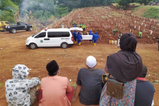 Family members watch as gravediggers bury the body of a COVID-19 patient at the Pondok Ranggon cemetery in East Jakarta, on Monday, September 14. 2020. Despite efforts to curb the outbreak, the death toll continues to climb and the cemetery is expected to be out of space by October. JP/P.J. Leo