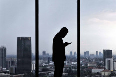 A Muamalat Bank employee uses his smartphone at work at the Muamalat Tower in Jakarta on Sept. 22. Finance Minister Sri Mulyani projects that Indonesia&rsquo;s economy will contract between 0.6 to 1.7 percent this year due to the COVID-19 pandemic. JP/Seto Wardhana.