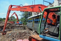 A worker cleans up garbage at the Manggarai sluice gate in South Jakarta on Sept. 22. Heavy rain a day before had caused garbage to pile up at the gate. The Jakarta Post/Seto Wardhana