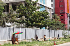 Street vendors serve customers behind the fence of Pademangan Athletes Village in North Jakarta on Sept. 25. The facility accommodates repatriated Indonesians who have been quarantined for suspected COVID-19 infection. JP/Seto Wardhana