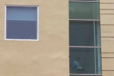 An asymptomatic COVID-19 patient sits by the window of Hotel U Stay in West Jakarta on Wednesday, September 30. 2020. The hotel has been turned into an isolation facility for asymptomatic and minor-symptomatic COVID-19 patients from West and South Jakarta. JP/P.J. Leo
