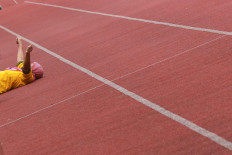 An asymptomatic COVID-19 patient rests on the ground following a round of morning physical exercises at the Patriot Candrabhaga Stadium isolation center in Bekasi, West Java, on October. 2. 2020. Physical exercise is deemed important to improve patients&rsquo; immune system against the coronavirus. JP/Dhoni Setiawan