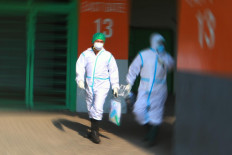 Medical personnel walk toward an ambulance assigned to pick up COVID-19 patients at the Patriot Candrabhaga Stadium in Bekasi, West Java, on October. 2. 2020. Asymptomatic patients from hospitals and local health centers will undergo isolation at the stadium. JP/Dhoni Setiawan
