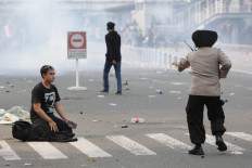 Cause for tears: A protesters sits in a road as tear gas fired by police obscures the scene behind him during a demonstration on Thursday, October 8. 2020 in Harmoni, Central Jakarta. Labor unions, students and members of the general public have been up in arms since Monday, when the House of Representatives gave its final approval for passing the job creation omnibus bill into law. JP/Wendra Ajistyatama