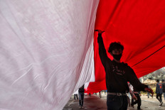 Divided nation: A student walks beneath a large Indonesian flag on Thursday, October 8. 2020 during a protest against the newly passed Job Creation Law on Jl. M.H. Thamrin in Central Jakarta. JP/Seto Wardhana 