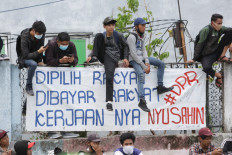 (Not) on the fence: Protesters sit on a wall above a banner during a peaceful demonstration on Thursday, October 7. 2020 in Harmoni, Central Jakarta. The banner gives voice to the protesters&rsquo; sense of public betrayal, pointing out that it is the people that elect and pay the salaries of lawmakers, only for them to &ldquo;cause trouble&rdquo;. JP/Wendra Ajistyatama