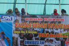 Putting their foot down: Members of a factory union stand behind a banner protesting the recently passed omnibus bill on job creation during a strike on Wednesday, October 7.2020 at the sports footwear factory of PT Panarub Industry in Tangerang. The banner calls on workers to answer to the &ldquo;challenge&rdquo;: &ldquo;Don&rsquo;t let them silence you. Reject and challenge the omnibus law on job creation.&rdquo; JP/Dhoni Setiawan