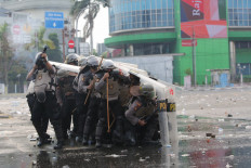 Close quarters: A policeman fires tear gas as other police officers take cover behind their shields on Thursday, October 8. 2020 during a protest in Harmoni, Central Jakarta. Civil society and rights groups on Thursday called on police to follow procedure and avoid using excessive force in dispersing protesters. JP/Wendra Ajistyatama 