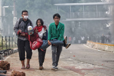 Unwitting casualty: Three men carry another man who was injured on Thursday, October 8. 2020 during a demonstration on Jl. M.H. Thamrin in Central Jakarta. Some protests over the three days since the Job Creation Law was passed on Monday have descended into violence, with fires and clashes reportedly breaking out in several cities. JP/Seto Wardhana