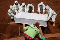 Cemetery workers place a coffin into a grave in Pondok Ranggon public cemetery in East Jakarta on Oct. 5. That day, the cemetery officially started using the newly expanded burial area for COVID-19 patients. JP/P.J. Leo