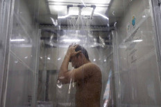 A doctor washes in a makeshift shower room during a decontamination simulation at Duri Pulo health community center in Central Jakarta on Oct. 6. The shower room is designed for medical workers who treat COVID-19 patients. JP/Wendra Ajistyatama
