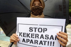 An activist from the Alliance Refusing to Forget (Aliansi Menolak Lupa) stands under a black umbrella in a silent protest in front on the Tugu Proklamasi (Proclamation Monument) in Central Jakarta, on Oct. 15. The activists protested against the police&rsquo;s repressive actions toward protesters during a series of rallies against the newly passed Job Creation Law. They called on the police to release detainees. JP/Wendra Ajistyatama