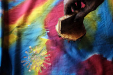 Nurohmad, 45, stamps a COVID-19 batik motif on a piece of fabric in Panggungharjo Bantul, Yogyakarta, on Oct. 11. The COVID-19 motif fabric sells for Rp 100,000 (US$6.80) to Rp 500,000 depending on the fabric&rsquo;s quality. JP/Donny Fernando
