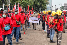 A Jakarta Public Order Agency (Satpol PP) officer holds up a banner on health protocols as workers protest the Job Creation Law in Jakarta on Nov. 17. The agency has urged protesters to wear masks and keep their distance to prevent the spread of COVID-19. JP/Seto Wardhana