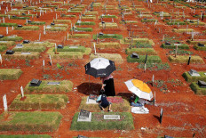 A family visits a grave at Pondok Ranggon cemetery in East Java on Nov. 20. The cemetery has run out of space to bury Muslims who have died of COVID-19 and has only 50 more spaces for Christian victims. Authorities are planning to bury further COVID-19 victims at the Tegal Alur cemetery in Kalideres, West Jakarta. JP/P.J. Leo