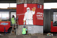 Graffiti artists embellish concrete pillars of the Cawang-Tanjung Priuk elevated toll road in East Jakarta on Dec. 4. Through the murals, the artists want to remind the public to adhere to health protocol. A day before, Indonesia shattered its COVID-19 daily record with more than 8,000 new cases. JP/P.J.Leo