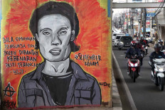 Motorists ride past a mural portraying missing activist and poet Wiji Thukul on Jl. Raya Ciledug, Cipulir, South Jakarta, on Dec. 10, coinciding with the commemoration of International Human Rights Day. JP/Seto Wardhana