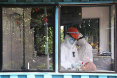 A medical worker takes a swab sample from a patient at the Pasar Minggu community health center (Puskesmas) in South Jakarta on Dec. 23. Authorities urged residents to check their health condition and adhere to strict health protocol by, among other measures, wearing masks and washing their hands regularly. JP/P.J. Leo