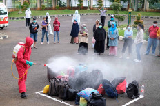 A medical worker sprays a disinfectant solution on bags carried by asymptomatic COVID-19 patients who just arrived at the isolation center at the Graha Wisata Ragunan in South Jakarta on Dec. 23. The patients will stay at the center for 14 days. JP/P.J. Leo