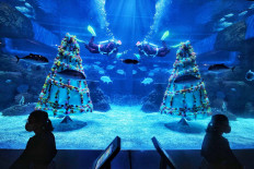 Visitors look at a performance by divers in Santa Claus costumes at the Jakarta Aquarium and Safari, at Neo Soho Mall, in Grogol, West Jakarta on Dec. 22, 2020. Thousands of aquatic and terrestrial animals are on display at the tourist spot, which is open to the public under tight enforcement of health protocol. JP/Seto Wardhana