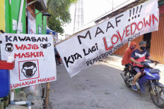Love in the time of corona: A couple on a motorcycle drives past a makeshift gate in a residential area in Citeureup, Bogor regency, West Java, on May 7. The gate displays a banner declaring a &ldquo;lovedown&rdquo; instead of a lockdown. JP/P.J.Leo