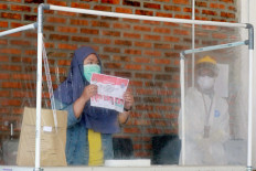 Polls amid pandemic: A COVID-19 patient casts her ballot as a health officer wearing personal protective gear looks on at a COVID-19 isolation facility that was treating 49 voters in South Tangerang city, Banten, on Dec.9. JP/ Dhoni Setiawan
