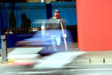 A day at a time: Street vendor Edi, an amputee, waits for traffic to slow down on Jan 22, 2021 in the Senen area of Central Jakarta. He sells pocket tissues for Rp 5,000 (36 US cents) per pack by approaching vehicles idling on the road. (JP/Dhoni Setiawan)