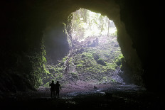 Into the light: We are naturally drawn to light and away from the dark, so will emerge into the light once again, like these two explorers walking toward the entrance from the pitch-black interior darkness of Jombang Cave in Gunung Kidul, Yogyakarta. (JP/R. Berto Wedhatama)