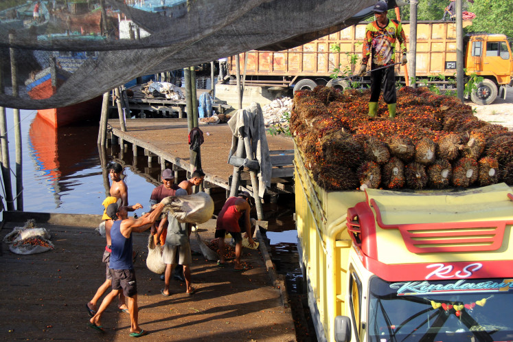 Workers load fresh fruits bunches (FFBs) onto a truck on May 23, 2024, at Sungai Mesjid Port in Dumai, Riau. Indonesia, the world&rsquo;s largest palm oil producer, has beenlooking to use biomass as a way to reduce costly fuel imports.