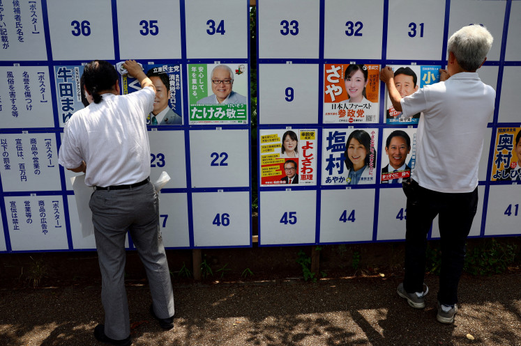 Supporters of candidates put up election campaign posters at the candidate bulletin board on the official campaign kick-off day for the July 20 upper house election, on the street in Tokyo, Japan July 3, 2025.